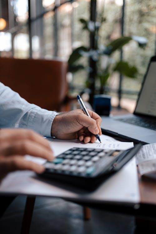 A person writing with a pen on their desk.